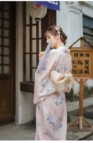 Woman wearing a soft pink kimono with a gold brocade Yukata bow belt. A graceful and traditional Japanese ensemble.