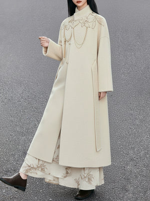 Long beige coat with floral embroidery on a plain background