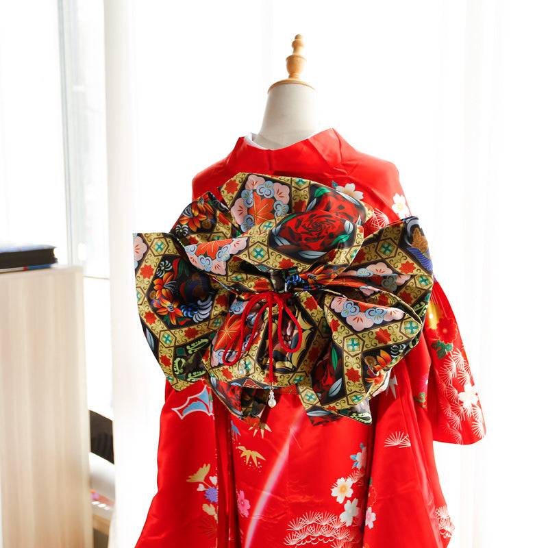 Red kimono with black and green floral big three-leaf bow belt. Traditional Japanese swinging sleeve design with geisha-style elegance.