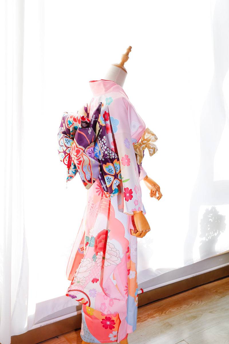 Side view of pink floral kimono with purple big three-leaf bow belt. Swinging sleeves and geisha-style belt bag add elegance.