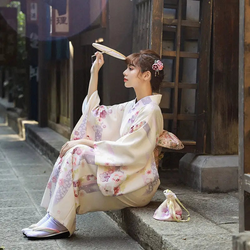 Elegant women's Japanese kimono dress in beige with cherry blossom patterns, perfect for the season. Traditional yukata style with obi belt.