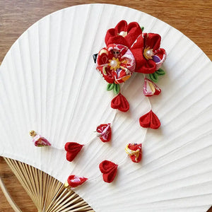 Handcrafted Japanese crepe hairpin with dangling red petals and floral motifs, a unique accessory for elegant hair styling.