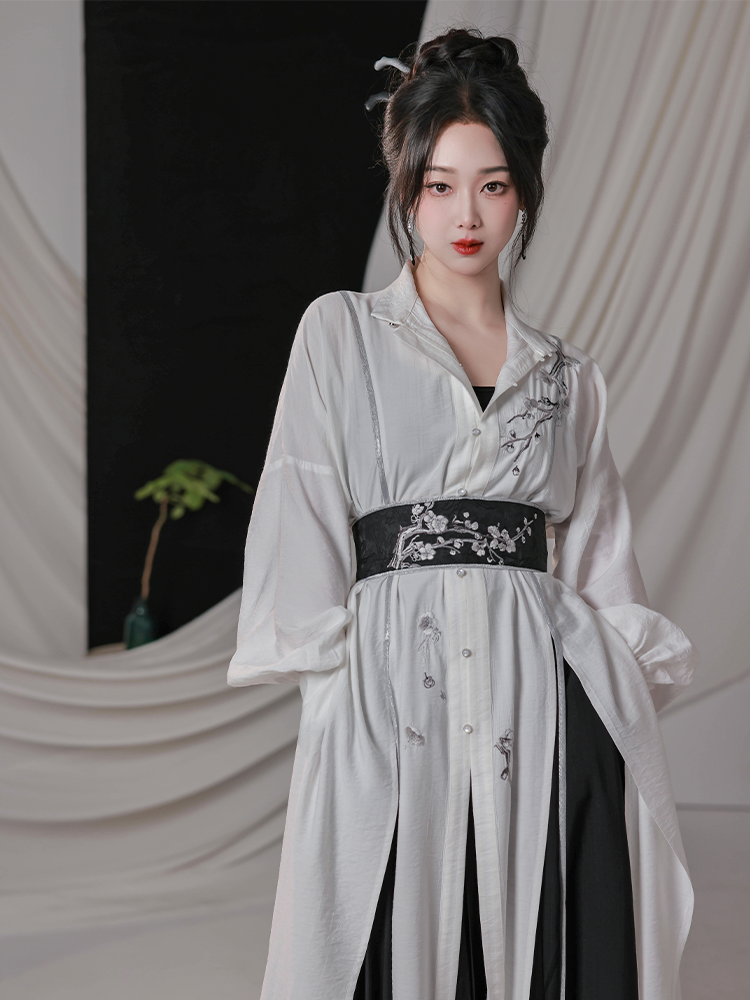 Close-up of black and white modern Hanfu shirt with plum blossom embroidery, paired with wide-leg pants and embroidered waist belt.