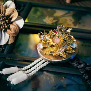 Silver Korean traditional headgear with gold floral and butterfly motifs, gemstone accents, and pearl tassels, finely crafted.