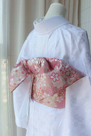 Back view of pink floral kimono brocade waist seal with bow, styled on white kimono. 120cm reversible cotton canvas accessory.