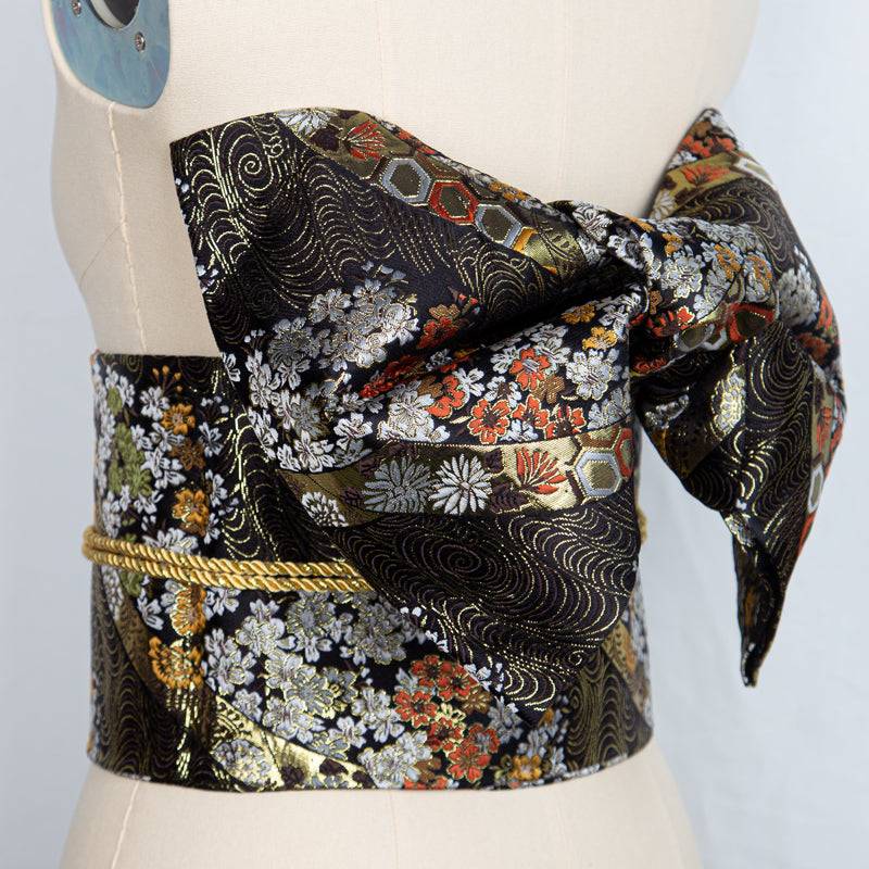 Black and gold floral brocade kimono waist seal with a structured bow, designed for traditional yukata styling and cultural photo sessions.