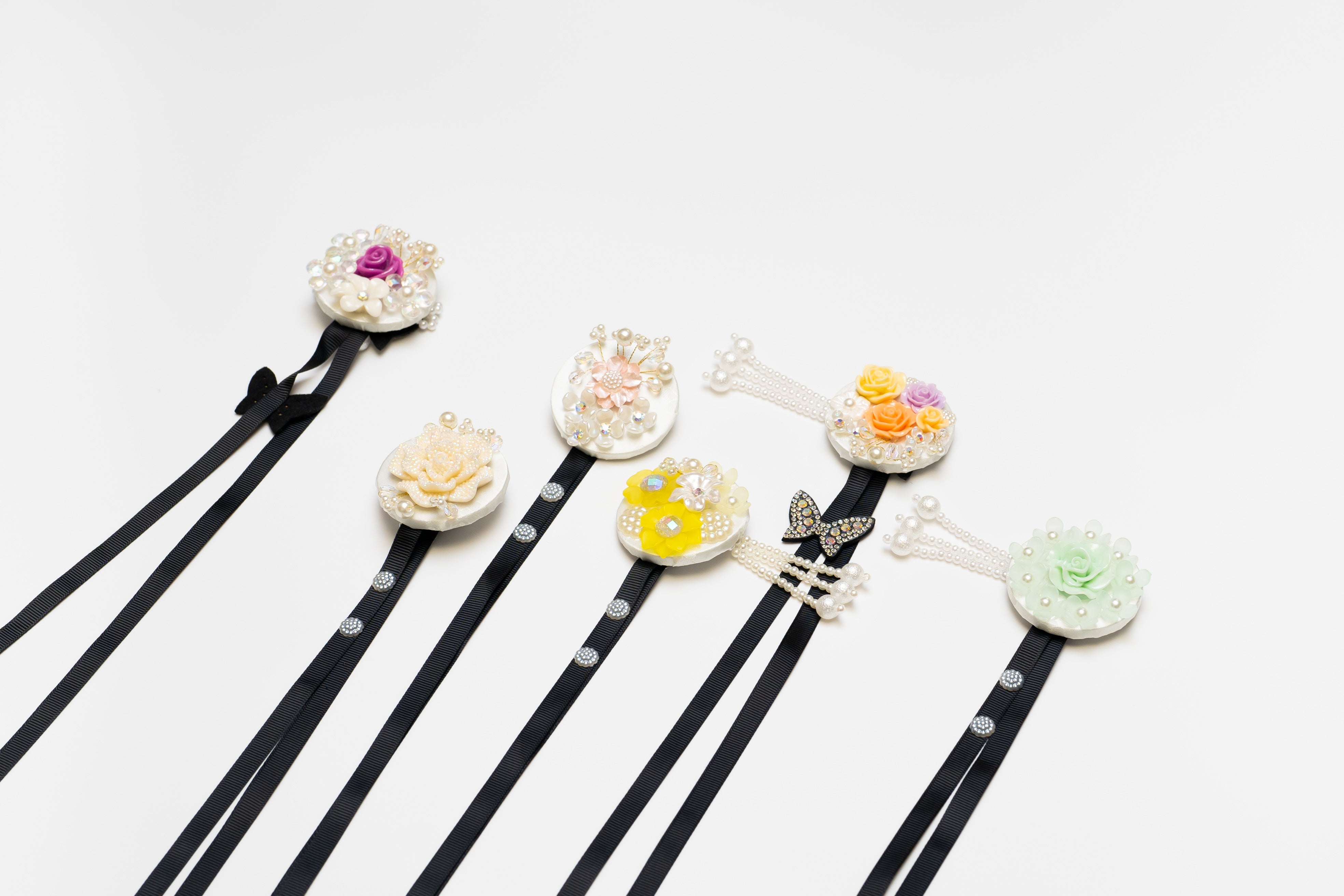 Assorted Korean traditional headgear accessories with floral and pearl designs on black ribbons, ideal for hanbok and cultural events.