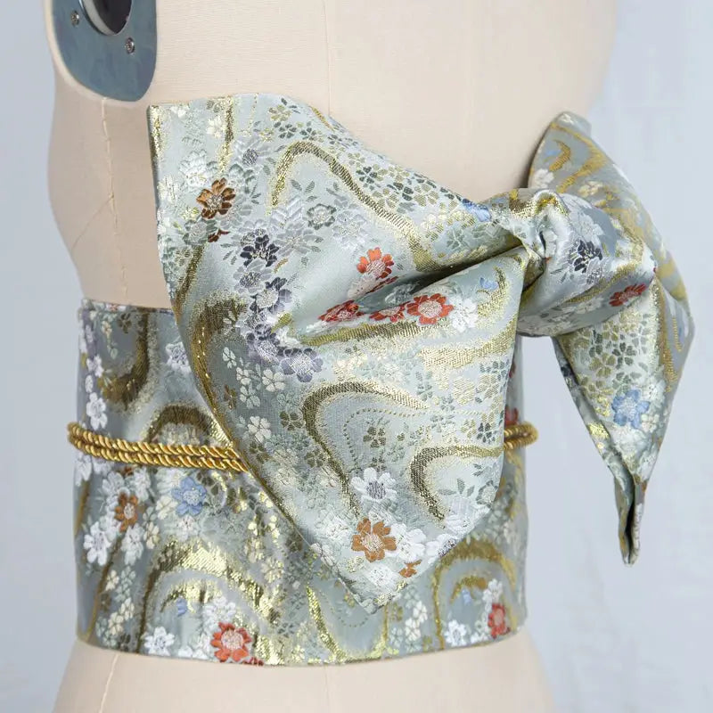 Light blue and gold floral brocade bow belt styled on mannequin, ideal for traditional Japanese yukata waist styling and photo shoots.