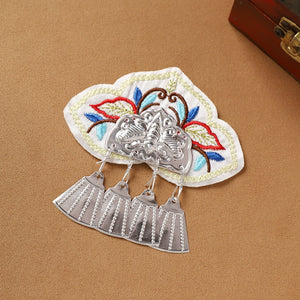 White embroidered Guizhou Miao fridge magnet with silver fan-shaped fringe, handmade ethnic refrigerator decoration.