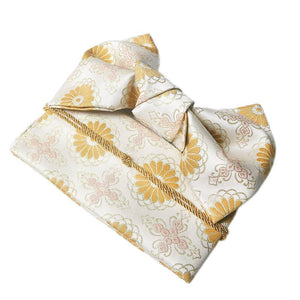 Folded gold and white brocade yukata belt with floral motifs and a decorative bow, ideal for kimono styling and traditional attire enhancement.