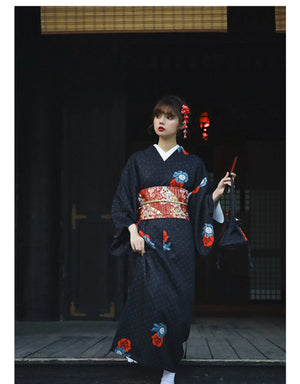 Black Japanese yukata with red and blue floral accents, styled with a red obi belt and traditional footwear. A timeless and elegant look.