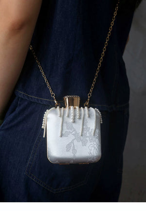 White mini bag worn with its chain shoulder strap