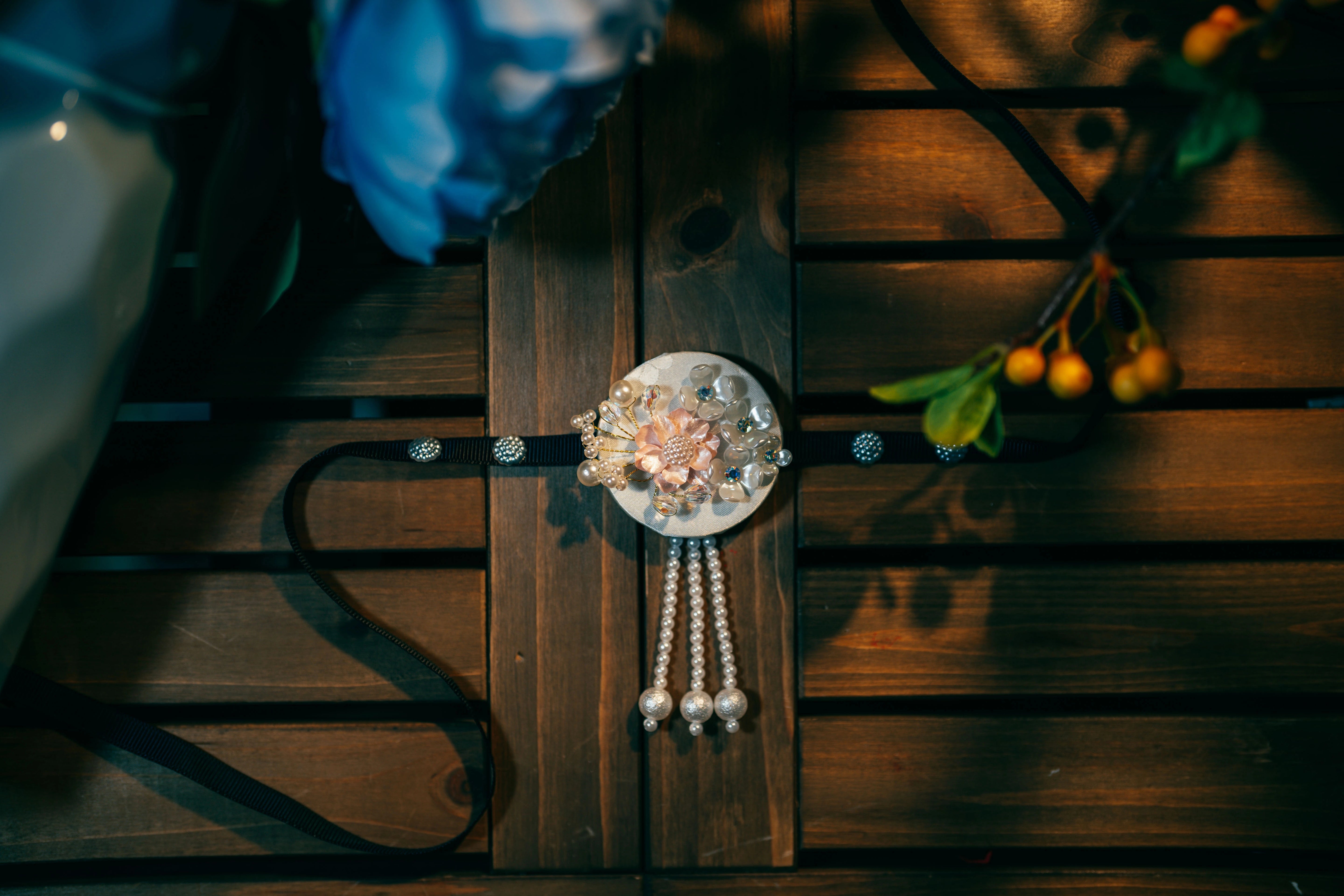 Detailed view of white and pink pearl Korean traditional headgear accessory with floral motif and pearl tassels on black ribbon.