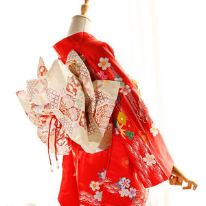 Side view of red kimono with cream and red big three-leaf bow belt. Swinging sleeves and geisha-style belt add traditional flair.