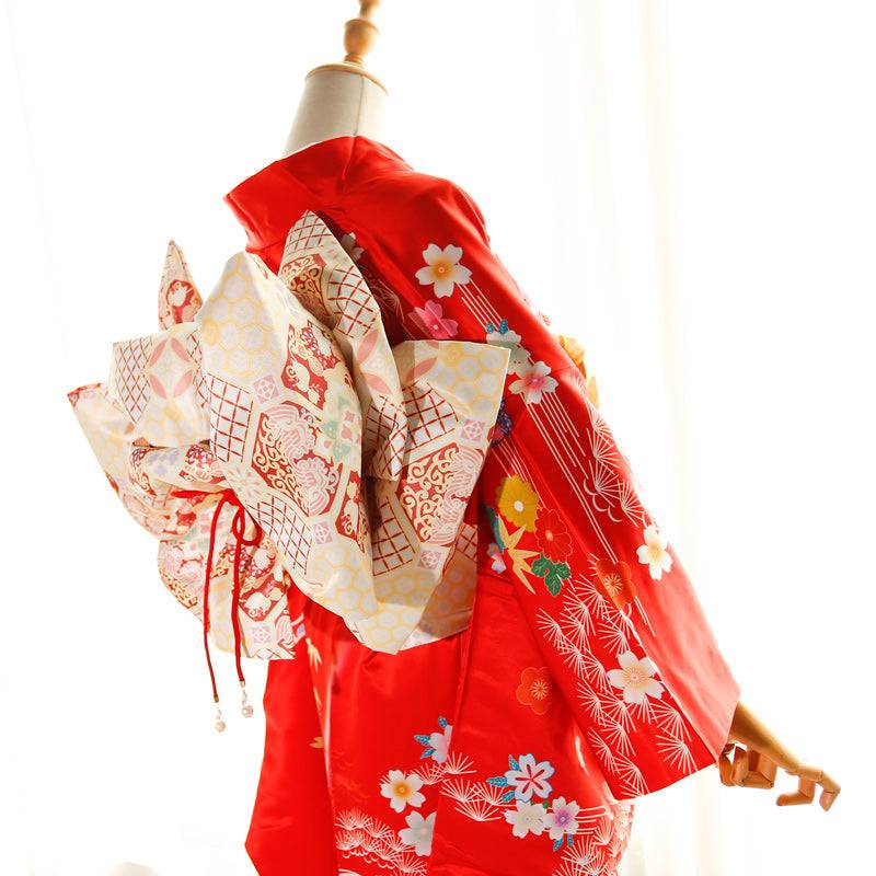 Side view of red kimono with cream and red big three-leaf bow belt. Swinging sleeves and geisha-style belt add traditional flair.
