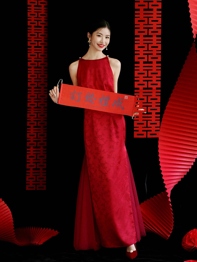 Smiling bride in red cheongsam dress with red scroll, perfect for traditional wedding or engagement events.