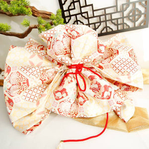 Close-up of cream and red big three-leaf bow kimono belt with red cord. Geisha-style accessory with traditional Japanese patterns.
