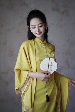 Bride in yellow Cheongsam with shawl and fan, styled for a traditional Chinese wedding toast or celebration.