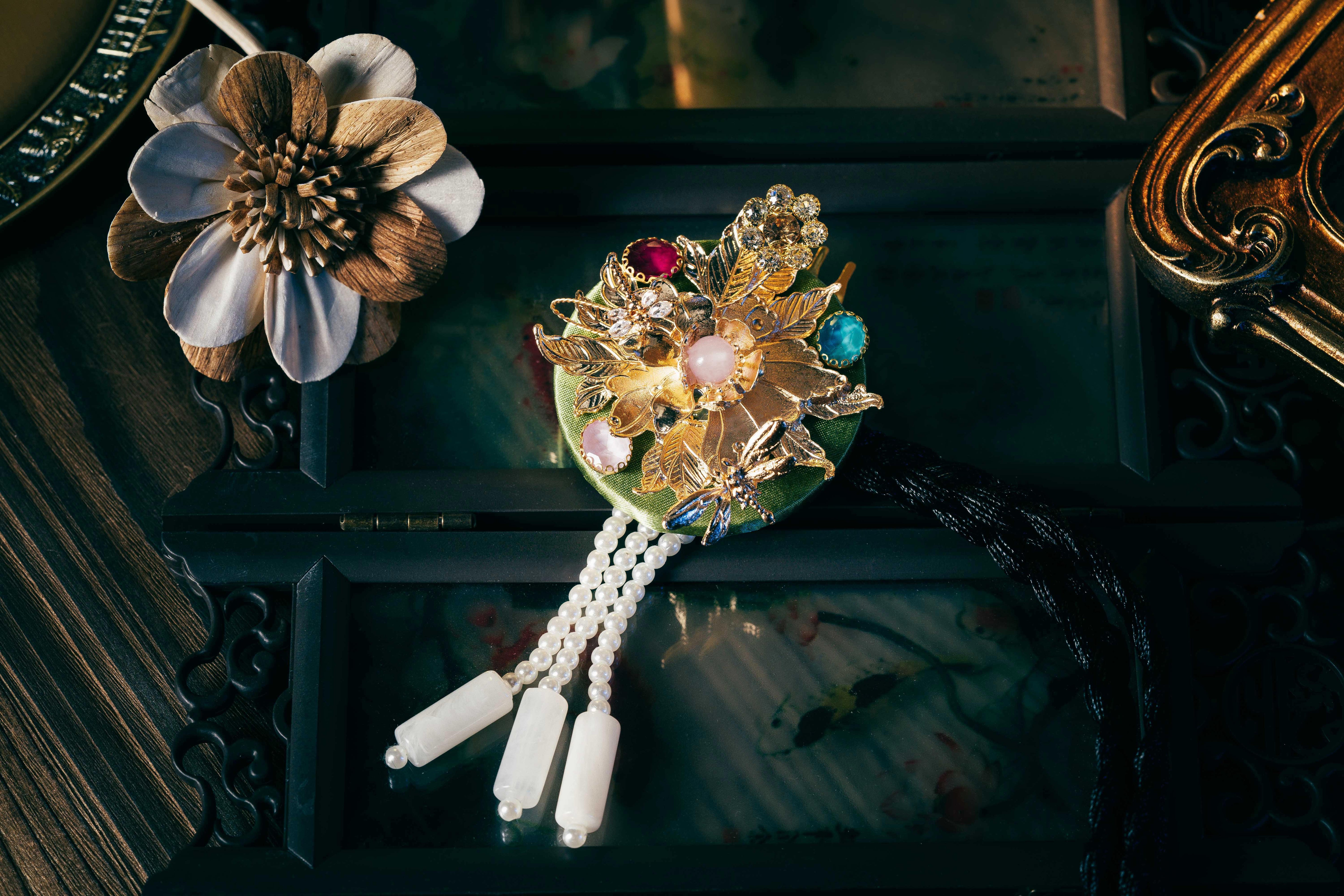 Green Korean traditional headgear with gold floral detailing and multicolored stones, finished with pearl tassels and fine cutting.