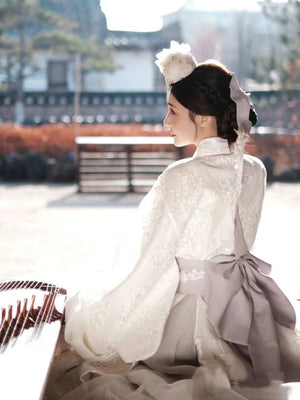 Back view of White Yanji Hanbok court dress with lavender ribbon and floral embroidery, traditional Korean fashion for cultural events.
