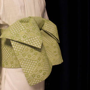 Side view of green lace kimono waist seal bow, showcasing intricate composite lace texture and wide structured shape.