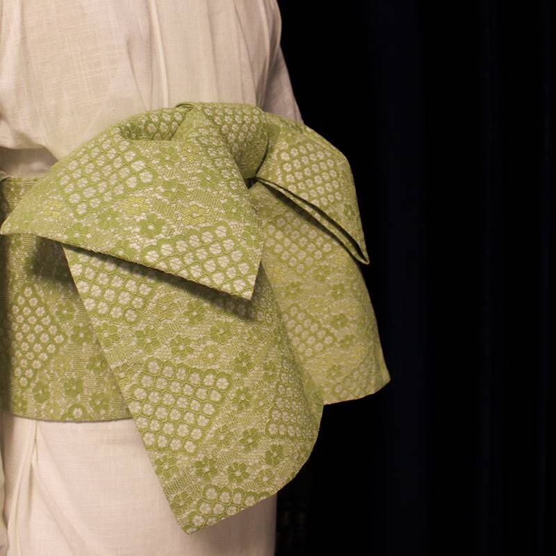 Side view of green lace kimono waist seal bow, showcasing intricate composite lace texture and wide structured shape.