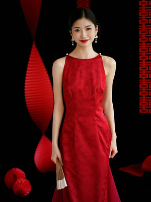 Smiling bride in red cheongsam wedding dress with pearl accents, perfect for engagement or toasting ceremonies.