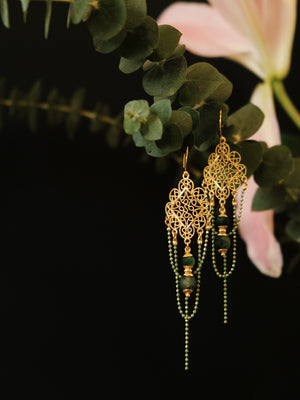 Su Mask Ear Clips - Hanfu Gold Tassel Earrings with green chalcedony beads, hanging on eucalyptus with soft pink lily in background.