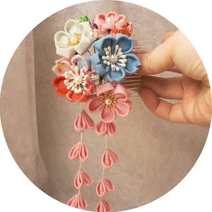 Hand holding Japanese crepe kimono hair comb featuring pastel flowers and cascading pink tassels, perfect for Hanfu photo shoots.