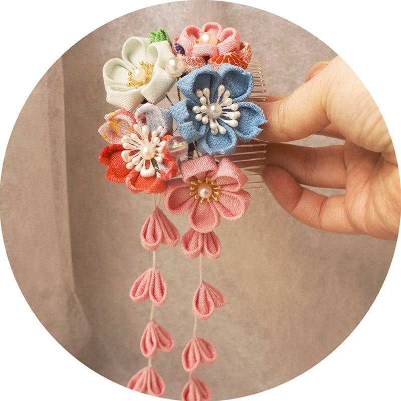 Hand holding Japanese crepe kimono hair comb featuring pastel flowers and cascading pink tassels, perfect for Hanfu photo shoots.