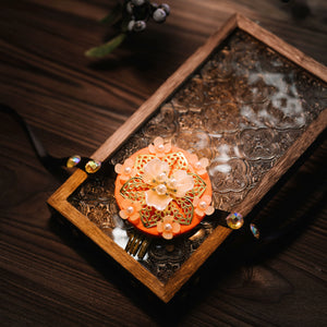Peach Korean traditional ethnic headgear with floral pearl design and pink beads, displayed on carved wooden tray.