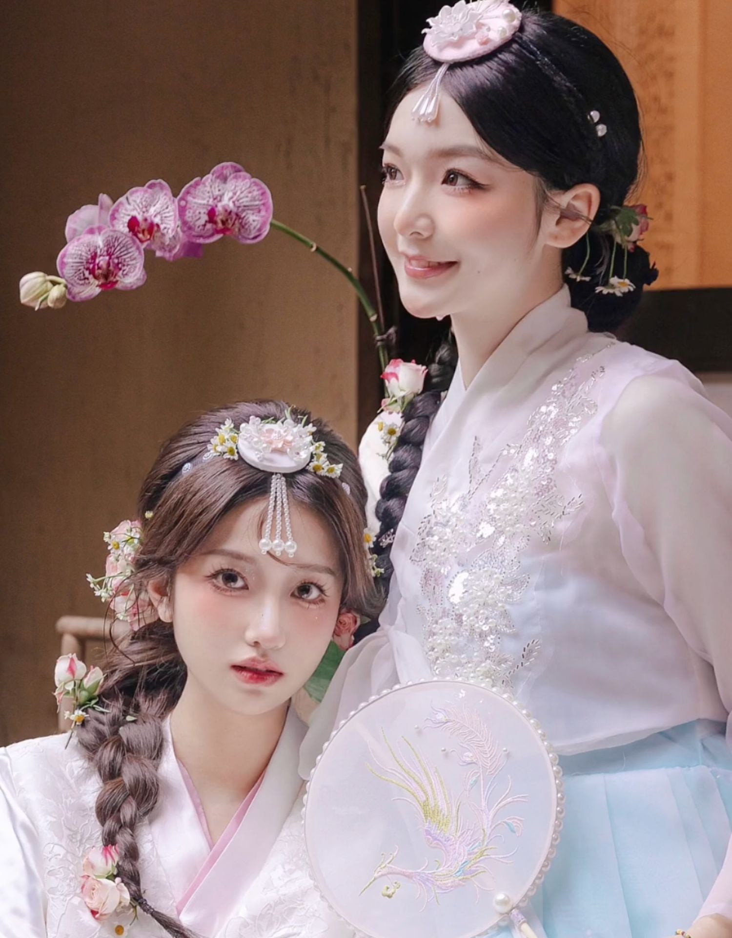Women dressed in hanbok adorned with white and pink pearl Korean traditional headgear accessories, highlighting traditional Korean beauty.