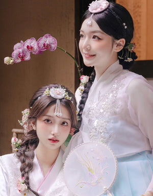 Women dressed in hanbok adorned with white and pink pearl Korean traditional headgear accessories, highlighting traditional Korean beauty.