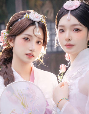 Two women in hanbok wearing Korean traditional headgear accessories with pearl and floral designs, showcasing cultural elegance.