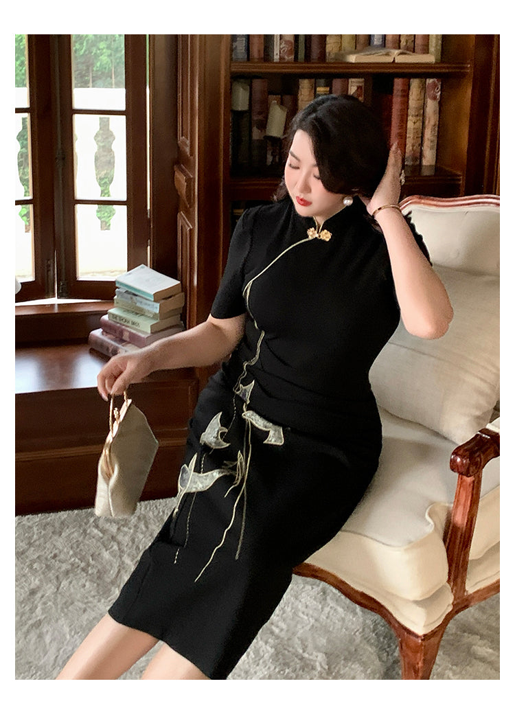 Plus size black cheongsam/qipao dress with gold bird embroidery, styled in a vintage armchair setting with bookshelves.