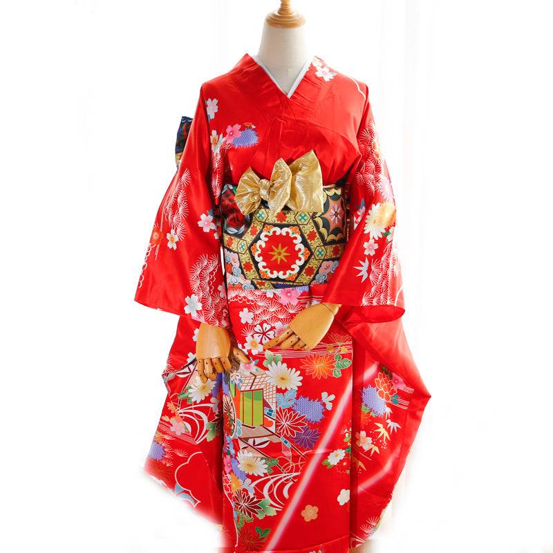 Red kimono with gold and black floral belt and swinging sleeves. Big three-leaf bow adds a traditional geisha-style touch.