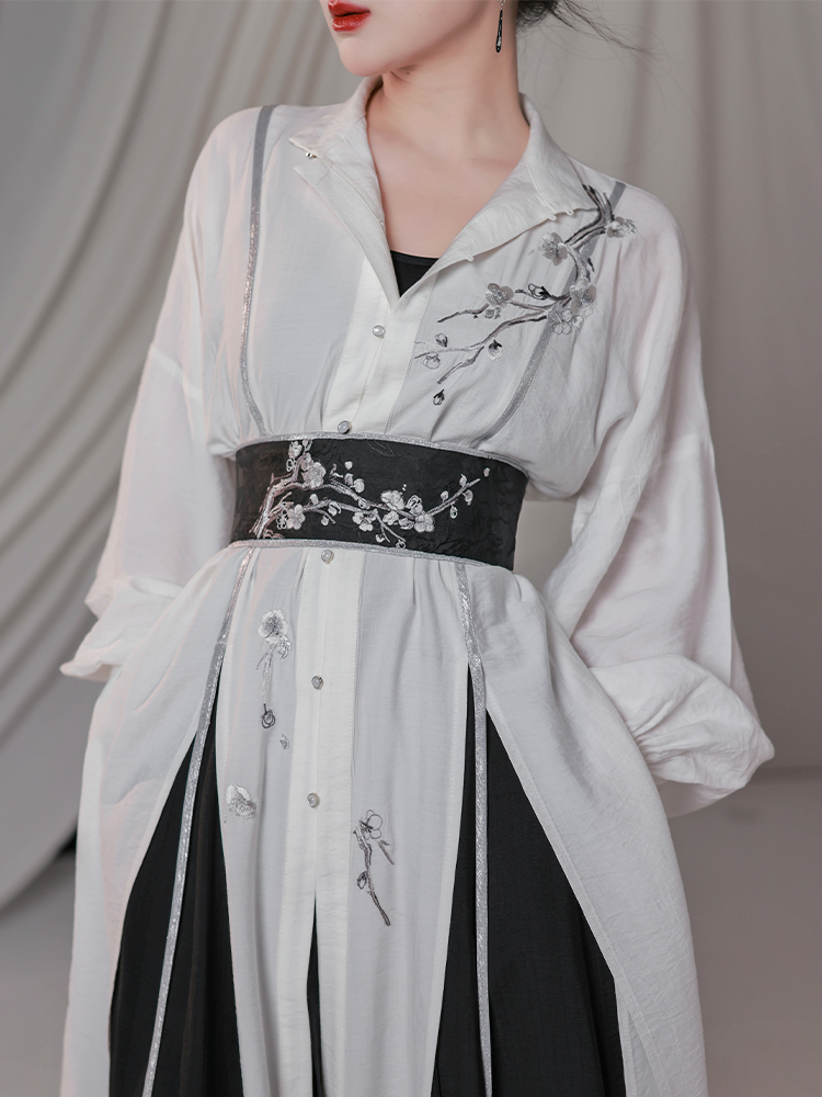 Detailed view of embroidered plum blossom design on white stand-up collar shirt, styled with a black floral waist belt in modern Hanfu fashion.