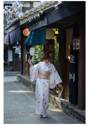 Elegant Japanese kimono dress for women, styled with a fan and matching bag. A refined yukata with cherry blossom motifs.