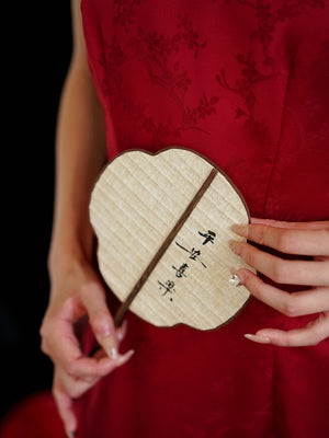 Detail of traditional fan held over red cheongsam wedding dress, ideal for engagement or bridal toasting.