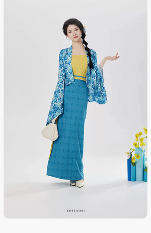 Model wearing Coconut Breeze Hanfu resort style outfit with yellow camisole, blue skirt, blue jacket, white bag