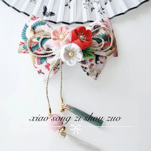 Elegant Japanese kimono hair clip with red and white cherry blossoms, floral bow, and green tassels.