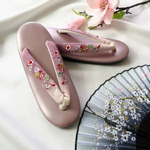 Soft pink Japanese kimono sandals with red floral embroidery and gradient herringbone straps. A delicate and stylish choice for formal wear.