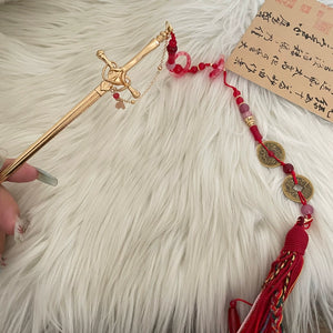 Ancient style shaking tassel hairpin featuring gold sword pin, red and pink beads, and Chinese coins, laid on faux fur background.