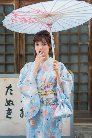 Elegant light blue kimono yukata with floral prints, styled with a traditional obi. A charming Japanese-inspired dress perfect for a graceful look.
