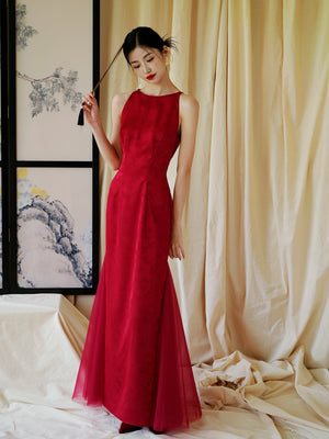 Bride in red cheongsam dress holding fan, styled for elegant wedding or engagement ceremonies.