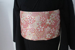 Flat view of pink floral kimono brocade waist seal without bow, worn over black kimono. 120cm reversible accessory with gold accents.