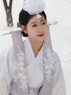 Close-up of White Yanji Hanbok court dress with floral embroidery and white headpiece, traditional Korean costume for cultural wear.