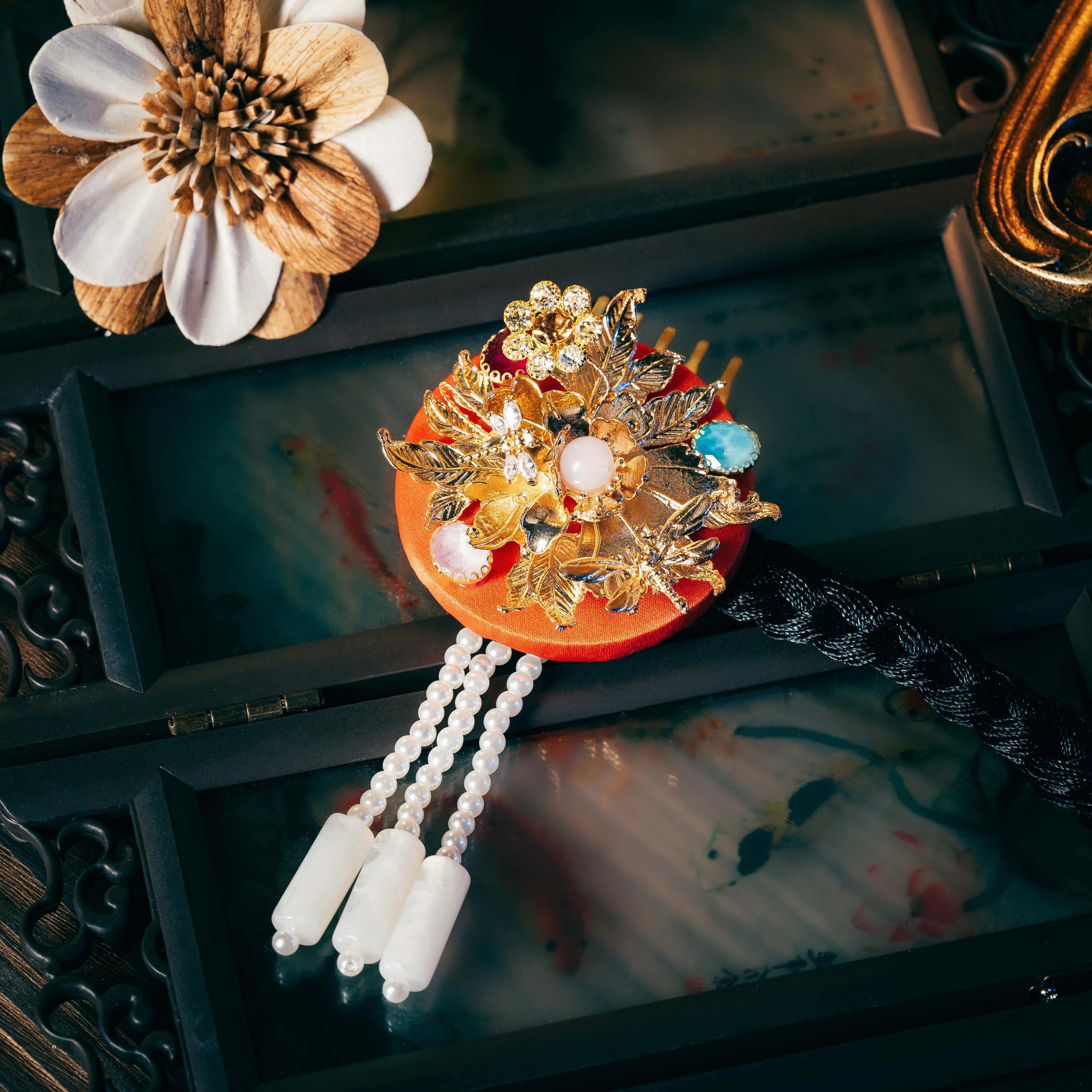 Red base Korean traditional ethnic headgear adorned with gold floral motifs, pearls, and gemstones, highlighting precise craftsmanship.