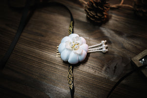 Yanji Folk Korean traditional White Hanbok headdress with pearl flower and gold trim, styled on rustic wooden surface.