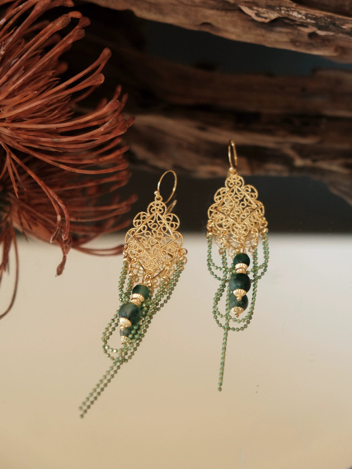 Su Mask Ear Clips - Hanfu Gold Tassel Earrings with water plant chalcedony and ornate filigree, displayed on reflective surface with floral decor.